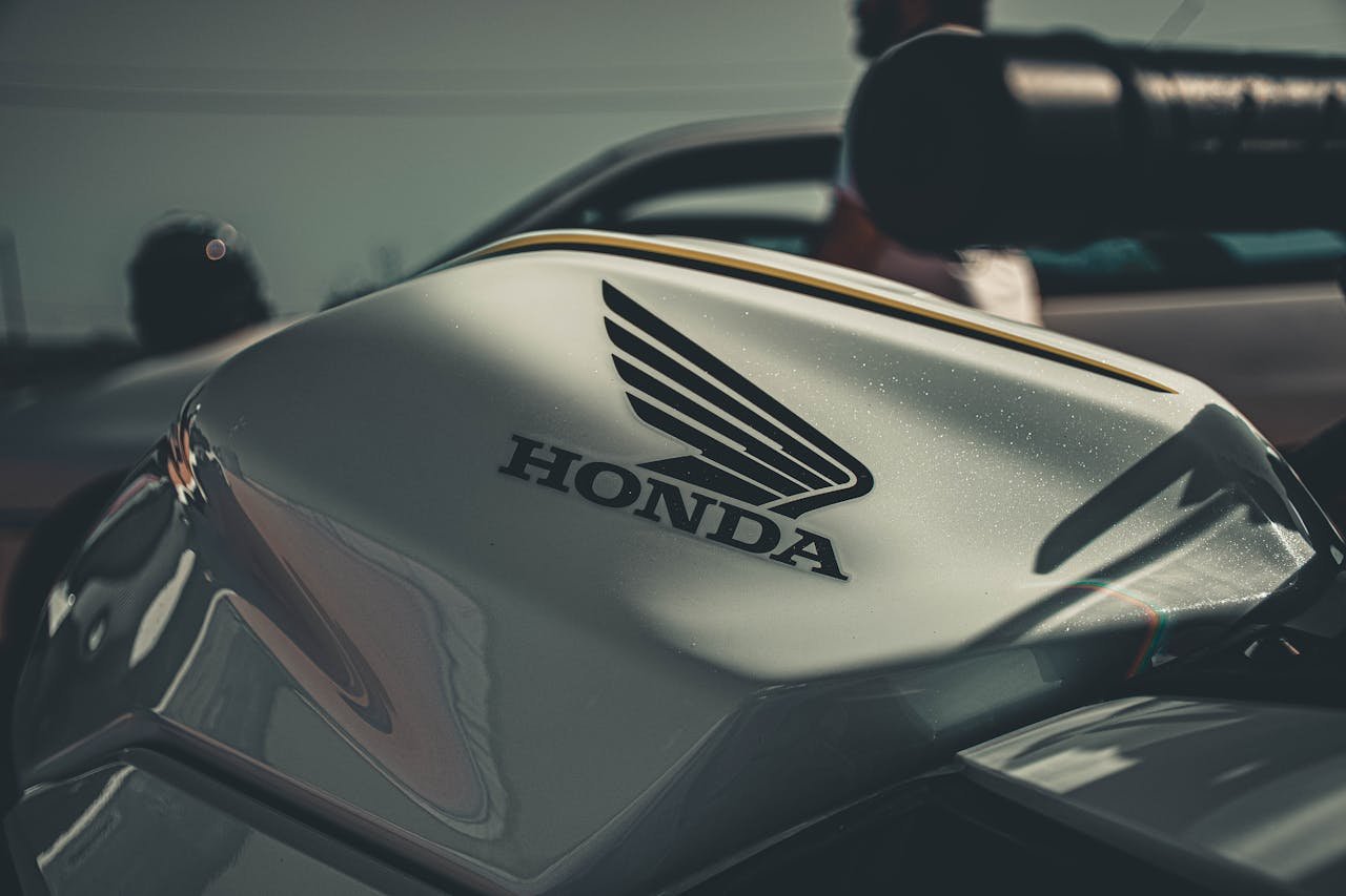 Detailed image of a Honda motorcycle tank and logo in a moody outdoor setting.